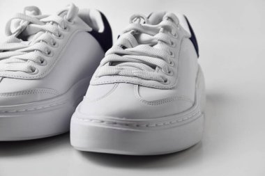 İzole edilmiş beyaz arka planda basit ve havalı beyaz spor ayakkabıların yakın plan fotoğrafı..