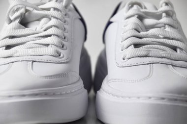 İzole edilmiş beyaz arka planda basit ve havalı beyaz spor ayakkabıların yakın plan fotoğrafı..