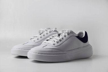 Sade beyaz arka planda bir çift parlak ve sade spor ayakkabısı modern ve temiz spor ya da günlük giysiler için..