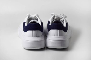 Bir çift sade ve şık beyaz spor ayakkabı. Arkadan bakıldığında, temiz beyaz bir arka planda izole edilmiş..