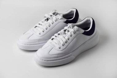 Sade beyaz arka planda bir çift parlak ve sade spor ayakkabısı modern ve temiz spor ya da günlük giysiler için..