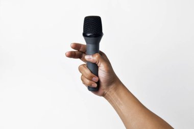 Asyalı bir el coşkuyla mikrofonu tutuyor, beyaz bir arka plana doğru yükseliyor. İfade, şarkı söyleme, topluluk önünde konuşma, protesto ve demokrasinin sembolü.