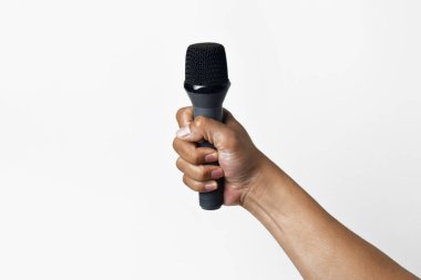 Asyalı bir el coşkuyla mikrofonu tutuyor, beyaz bir arka plana doğru yükseliyor. İfade, şarkı söyleme, topluluk önünde konuşma, protesto ve demokrasinin sembolü.