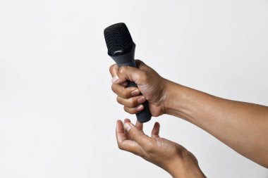 Asyalı bir adamın el ele tutuşması ve beyaz arka planda izole edilmiş bir mikrofon kullanması. Şarkı söyleme, konuşma, direniş, ifade ve demokrasi kavramı.