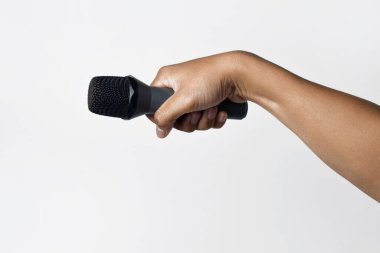 Asyalı bir adamın el ele tutuşması ve beyaz arka planda izole edilmiş bir mikrofon kullanması. Şarkı söyleme, konuşma, direniş, ifade ve demokrasi kavramı.