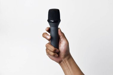 Aşağıdan beyaz izole edilmiş bir arka planı olan bir mikrofon tutan kişi. Konuşmanın, şarkı söylemenin, direnişin ve demokrasinin sembolü.