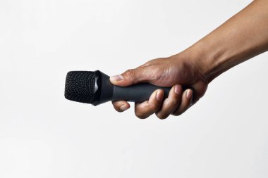 Yukarıdan izole edilmiş beyaz bir arka planı olan bir mikrofon tutan kişi. Konuşma, şarkı söyleme, direniş ve demokrasinin sembolü.