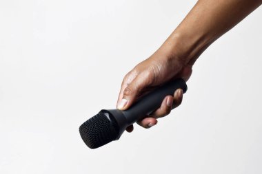 Yukarıdan izole edilmiş beyaz bir arka planı olan bir mikrofon tutan kişi. Konuşma, şarkı söyleme, direniş ve demokrasinin sembolü.