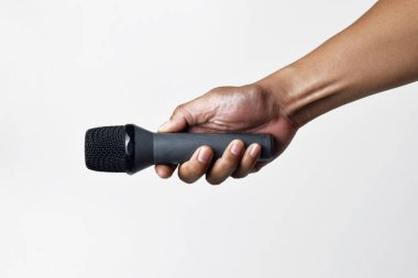 Yukarıdan izole edilmiş beyaz bir arka planı olan bir mikrofon tutan kişi. Konuşma, şarkı söyleme, direniş ve demokrasinin sembolü.