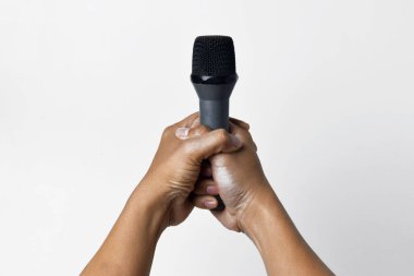 İzole edilmiş beyaz bir arka planda mikrofon tutan Asyalı bir adamın iki elinin yakın çekimi. Şarkı söylemenin, sesin, direnişin ve demokrasinin sembolü.