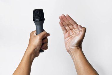 Asyalı bir adamın bir eli mikrofon tutarken diğer eli beyaz bir arka planda yukarı doğru yalvarıyor. Şarkı söylemenin, sesin, direnişin ve demokrasinin sembolü.