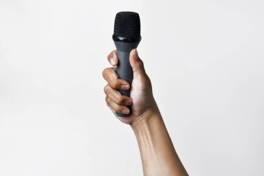Asyalı bir adamın elinin beyaz izole edilmiş bir arka plana mikrofon tutarken yakın plan görüntüsü. Şarkı söyleme, konuşma özgürlüğü, ifade özgürlüğü, direniş ve demokrasi kavramı.