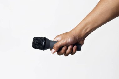 Asyalı bir adamın el ele tutuşması ve beyaz arka planda izole edilmiş bir mikrofon kullanması. Şarkı söyleme, konuşma, direniş, ifade ve demokrasi kavramı.