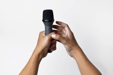 Asyalı bir adamın bir eli mikrofon tutarken diğer eli beyaz bir arka planda yukarı doğru yalvarıyor. Şarkı söylemenin, sesin, direnişin ve demokrasinin sembolü.