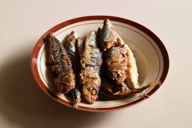 Bazı geleneksel Endonezya kızarmış balıkları izole edilmiş krema arka planlı bir tabakta servis edilir..