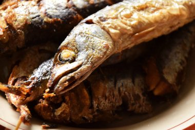 Birkaç geleneksel Endonezya kızarmış balığının balık kafaları izole edilmiş krema arkaplanlı bir tabakta servis ediliyor..