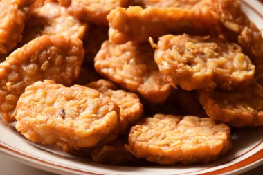 Endonezya usulü kızarmış Tempeh 'e yakın çekim. Izole edilmiş krema arkaplanlı lezzetli bir tabakta. Üretici Ai