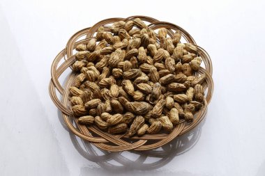 Doğal ahşap pipetten yapılmış bir tabakta bir demet tuzlu fıstık var. Beyaz zemin arkaplanı olan.