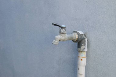 Çeşme kirlenmeye ve üzerinde beton izleri olan musluk beyaz bir duvardaydı..