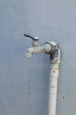 Çeşme kirlenmeye ve üzerinde beton izleri olan musluk beyaz bir duvardaydı..