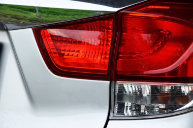 Modern kırmızı beyaz bir arabanın arka lambası, gümüş renkli bir araba gövdesine sahip..