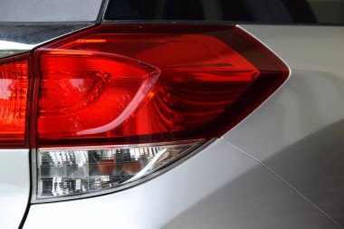 Modern kırmızı beyaz bir arabanın arka lambası, gümüş renkli bir araba gövdesine sahip..