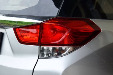 Modern kırmızı beyaz bir arabanın arka lambası, gümüş renkli bir araba gövdesine sahip..