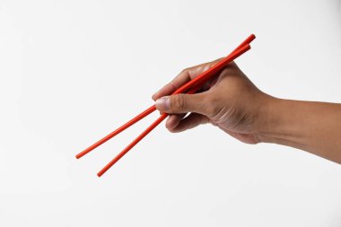 Bir adamın eli kırmızı yemek çubuğunu sanki beyaz izole edilmiş bir arka planı varmış gibi tutar..