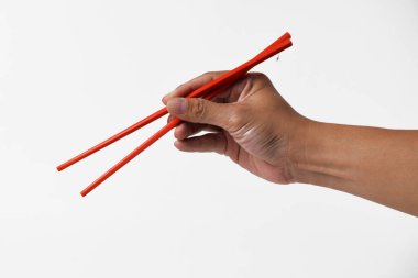 Bir adamın eli kırmızı yemek çubuğunu sanki beyaz izole edilmiş bir arka planı varmış gibi tutar..