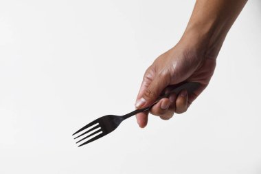 Asyalı bir adamın elinde tepeden tırnağa çelik bir çatal tutarken, sanki izole edilmiş beyaz bir arka planda yemek yiyormuş gibi bir ifade var..