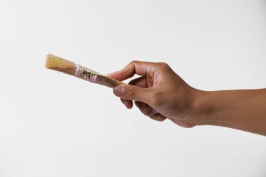 İzole edilmiş beyaz bir arka planda resim yapmak için fırça tutan bir adam..