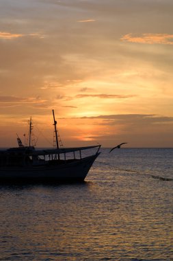 Karayip Denizi kıyısında sakin bir akşam: Güneş, Gökyüzünü Turuncuya ve Kızıla boyar gibi demirlemiş balıkçı tekneleri.
