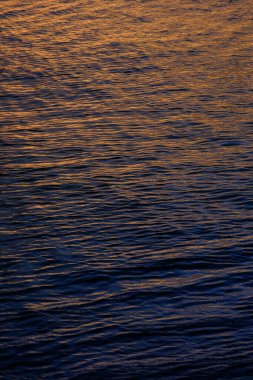 Sunset Serenity: Küçük Dalgalar ve Metalik Renkler Denizin Sakinliğini Yansıtıyor