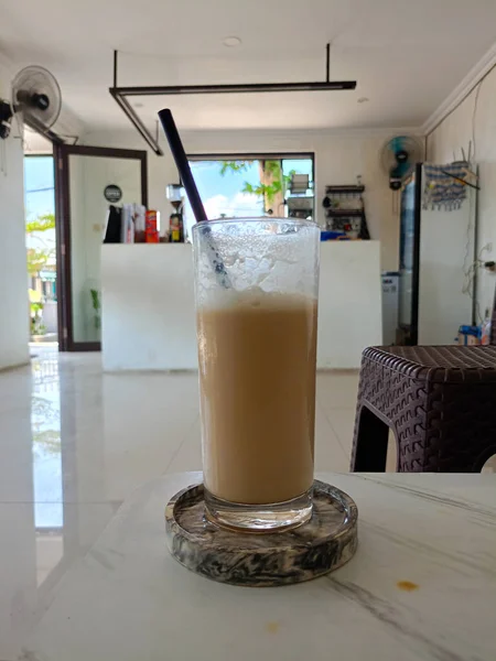 Bir bardak sütlü buzlu kapuçino. Buzlu kahve. Bir kafede ya da restoranda bir masada.