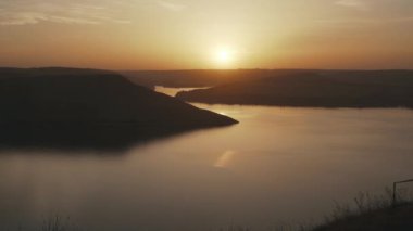 Nehir ve tepelerin ardında güzel bir günbatımı.