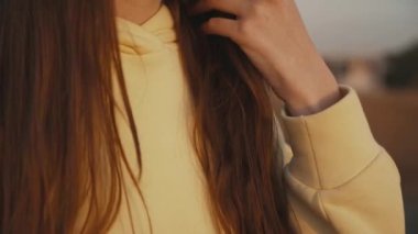 Kız elini saçlarında gezdiriyor. Hafif bir rüzgar saçlarını savuruyor..