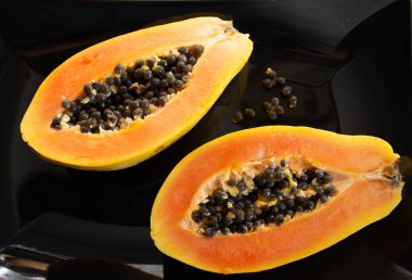 Papaya siyah arka planda ikiye bölünmüş.