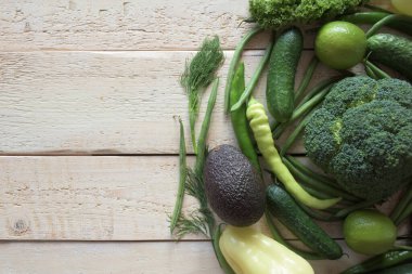 Hafif ahşap arka planda taze yeşil sebzeler. Diyet yeşil organik sebzeler