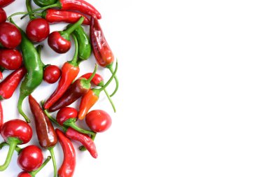 Acı biber yığını, yazı için boşluk ile sınırdır. Farklı yeşil ve kırmızı kırmızı kırmızı biberler beyaz arka planda izole edilmiş. Kiraz ve küçük acı biber.
