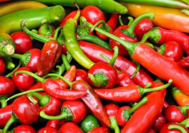 Farklı acı biber yığınları. Yeşil ve kırmızı acı biber arka planı. Kiraz ve küçük acı biber.