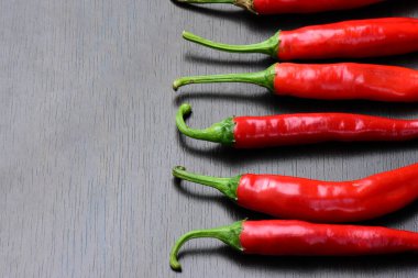 Kırmızı biberler beyaz arka planda izole edilmiş, üst görünümde, sırada. Cayenne biberi, Anaheim biberi, uzun kırmızı biber izole edilmiş. Dikey acı biber sırası. 