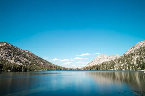Toxaway Gölü, Idahos Sawtooth Wilderness 'da bir yaz günü mavi gökyüzü, beyaz bulutlar ve el değmemiş Alp Gölü' nün sakin sularında bir yansıma ile görüldü..