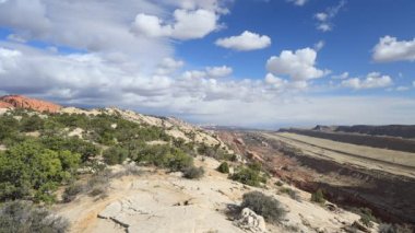Waterpocket Katlaması, Utah 'taki Capitol Reef Ulusal Parkı' nda 160 km uzunluğunda bir jeolojik özellik. Gökyüzünde beyaz bulutlar görülür. Tanımlanamayan yürüyüşçülerden oluşan bir grup.