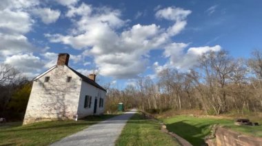 Edwards Ferry Lockhouse, Maryland, Poolesville 'de güzel bir sonbahar gününde C & O Canal National Historic Park Towpath' de. Kümülüs bulutları gökyüzünden geçer. Kilit görevlileri bir zamanlar bu binada yaşarmış..