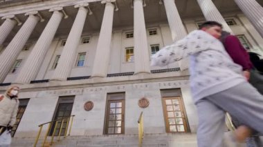 Washington, DC 'deki Hazine Bakanlığı' nın 15. sokak girişi. Devriye gezen bir polis memuru geçiyor. Ultra geniş, düşük açılı çekim.