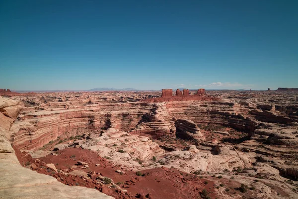 Utah 'taki Canyonlands Ulusal Parkı' nın Labirent Bölgesi 'nden görüntüler. Ufukta birkaç bulut görülür. Bunun dışında açık bir gökyüzünde. Kanyonlardan oluşan bir labirent görünür..