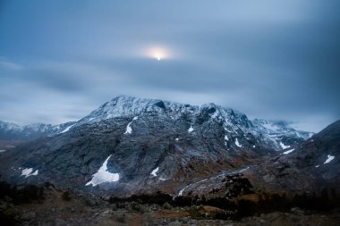 Ay, Wyoming 'in Wind River Range bölgesindeki Bull Lake Creek' in North Fork 'undaki kar fırtınasından sonra karlı tepelerin üzerinde asılı duruyor..  