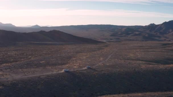 两辆越野车驶过加州Tecopa东部的沙漠 背景是Amargosa河谷和Avawatz山脉 — 图库视频影像