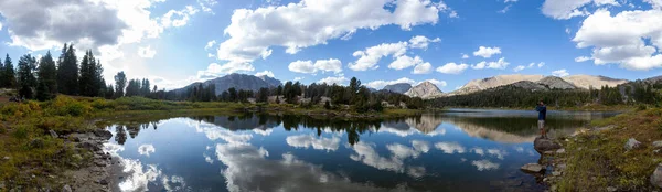 Wyoming 'in Wind River Range bölgesindeki Kurukafa Gölü' nün kenarında kameralı bir yürüyüşçü manzarası. Uzakta, soldan sağa, Mt. Geikie, MT 'den. Hooker, Piramit Tepesi ve Dike Dağı görünüyor..