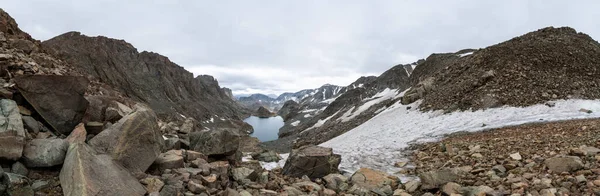 Alpine Lakes Havzası 'nın Alpine Lakes Geçidi' nden güneye bakan manzarası. Kar tarlaları ve karla kaplı tepeler uzaklardan görülür.